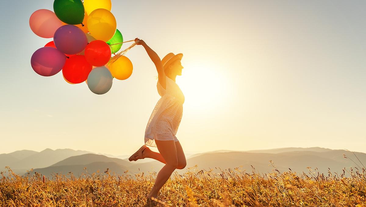 happy woman with balloons at sunset in summer